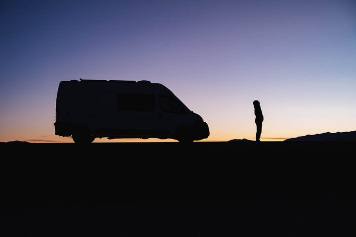 Silhouette of Maxine and the van at sunset. Maxine looking up to the sky. Salinas Grandes. Jujuy Province - Argentina