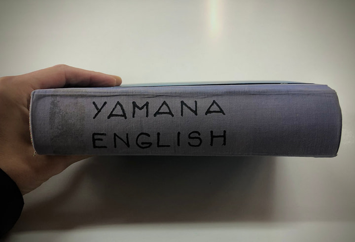 Maxine's hand holding the Yamana - English dictionary