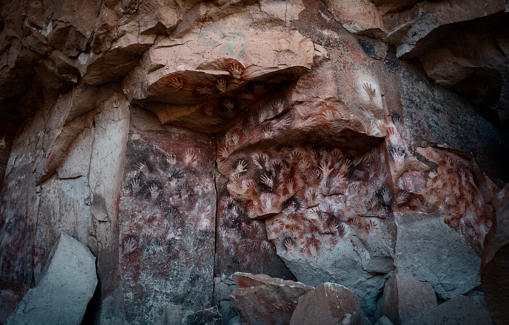 The iconic pre-historic hand prints outlined against the rock of in different coloured pigments at Cueva the Las Manos (Cave of Hands)