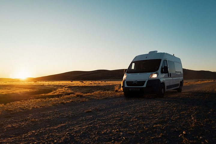 our campervan in the estepa (steppe) at sunset with the headlights on